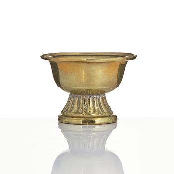 A bronze deity and a brass sacrificial bowl, Tibet, circa 1900.