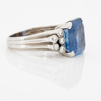 An 18K white gold ring set with a faceted sapphire and round brilliant-cut diamonds.
