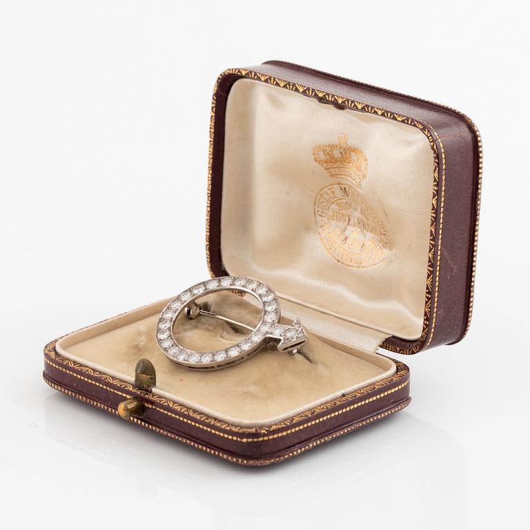 An 18K white gold brooch set with round brilliant-cut diamonds.