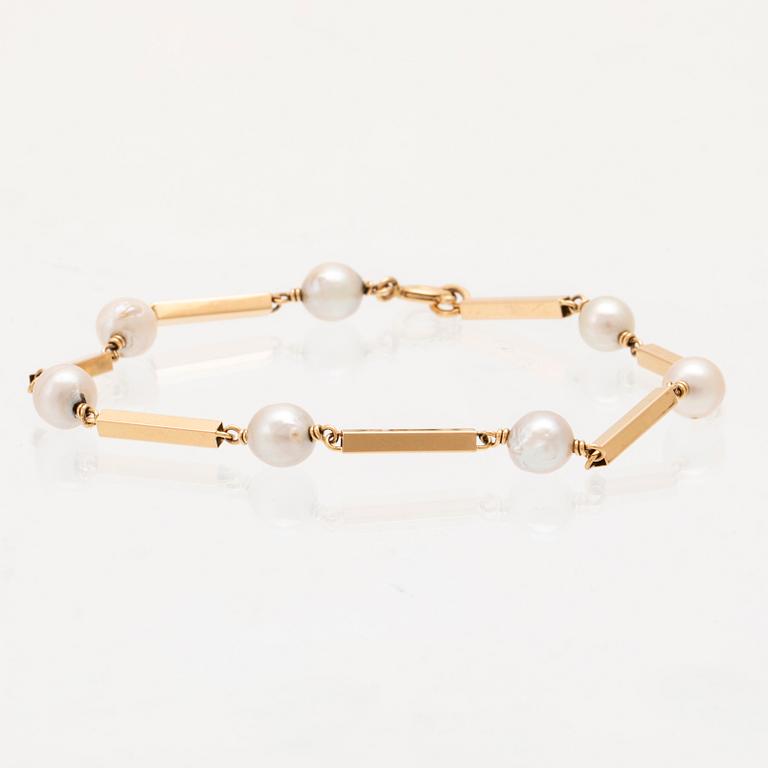 An 18K gold bracelet set with cultured pearls.
