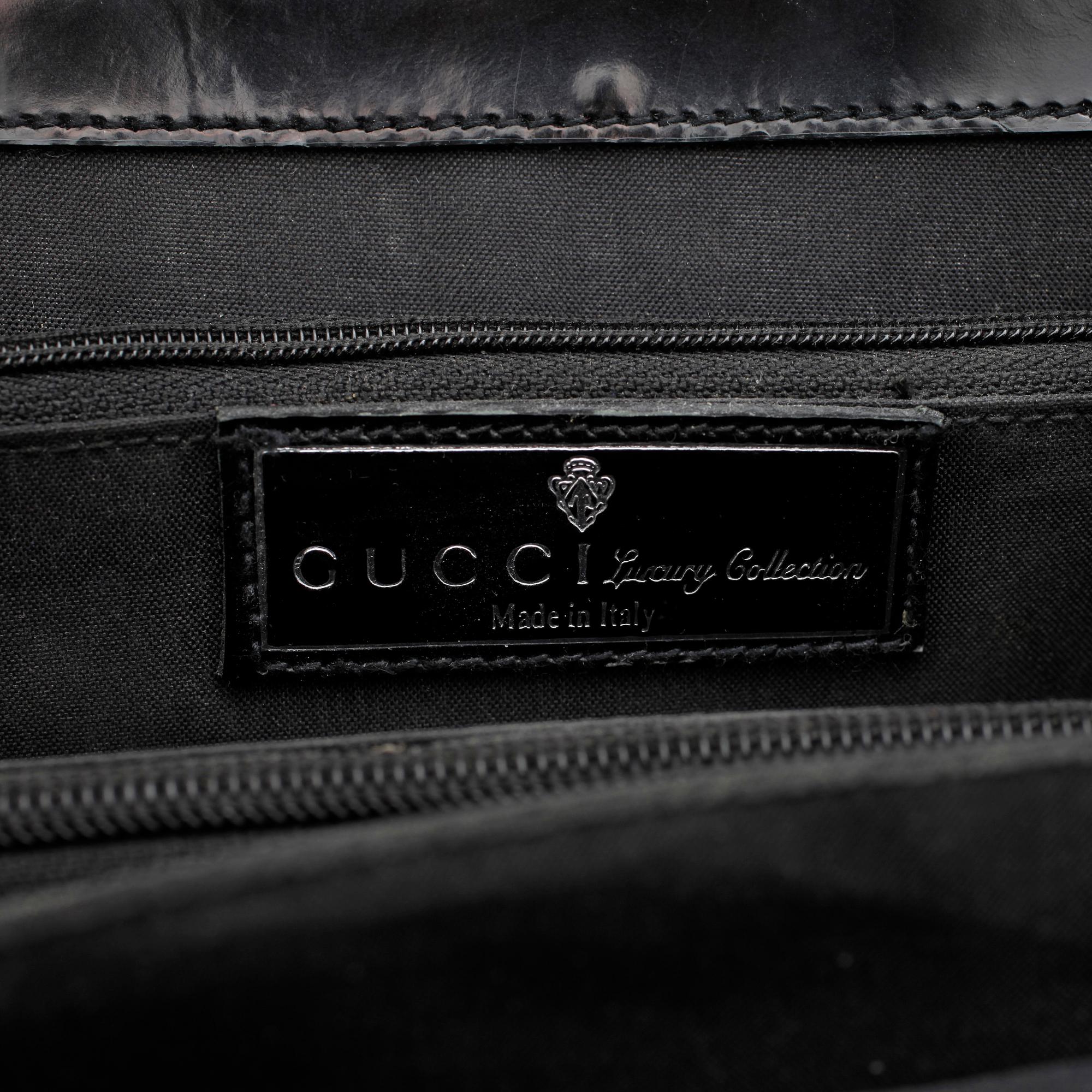 GUCCI, a black patent leather handbag.
