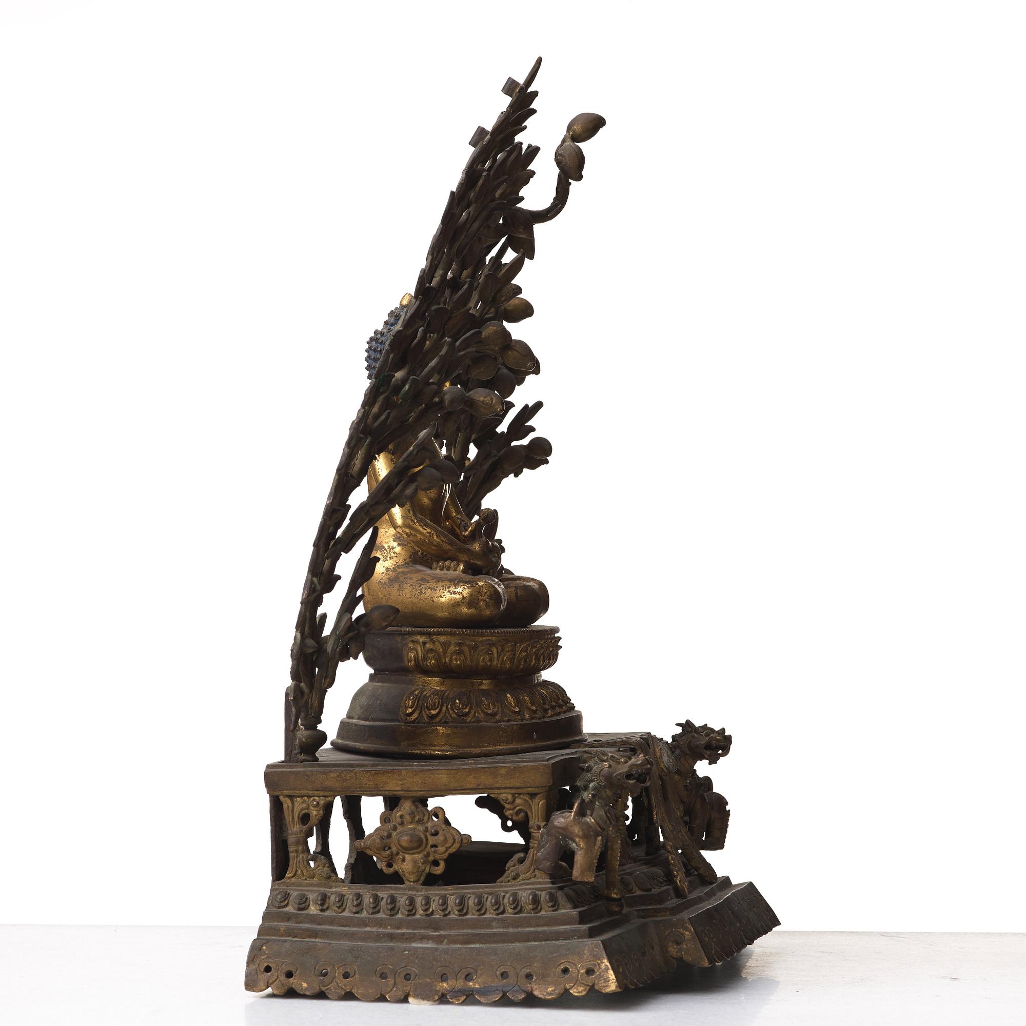 A large Nepalese gilt bronze buddha on a throne with mandorla, 18/19th Century.