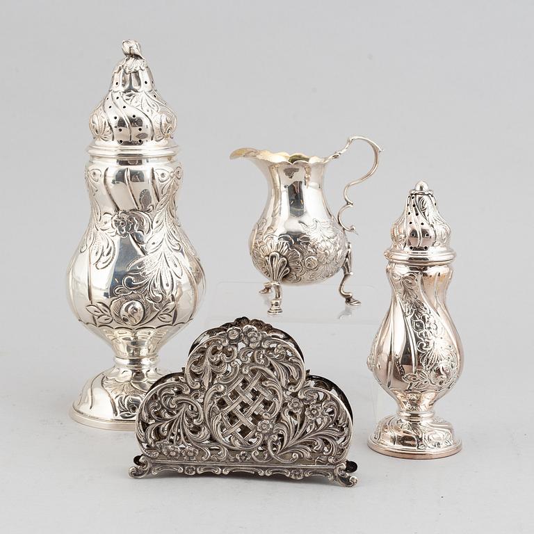 A silver sugar shaker, salt shaker, creamer and napkin holder.