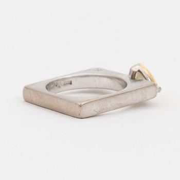 A ring set with a trilliant-cut diamond and small round, brilliant-cut diamonds.