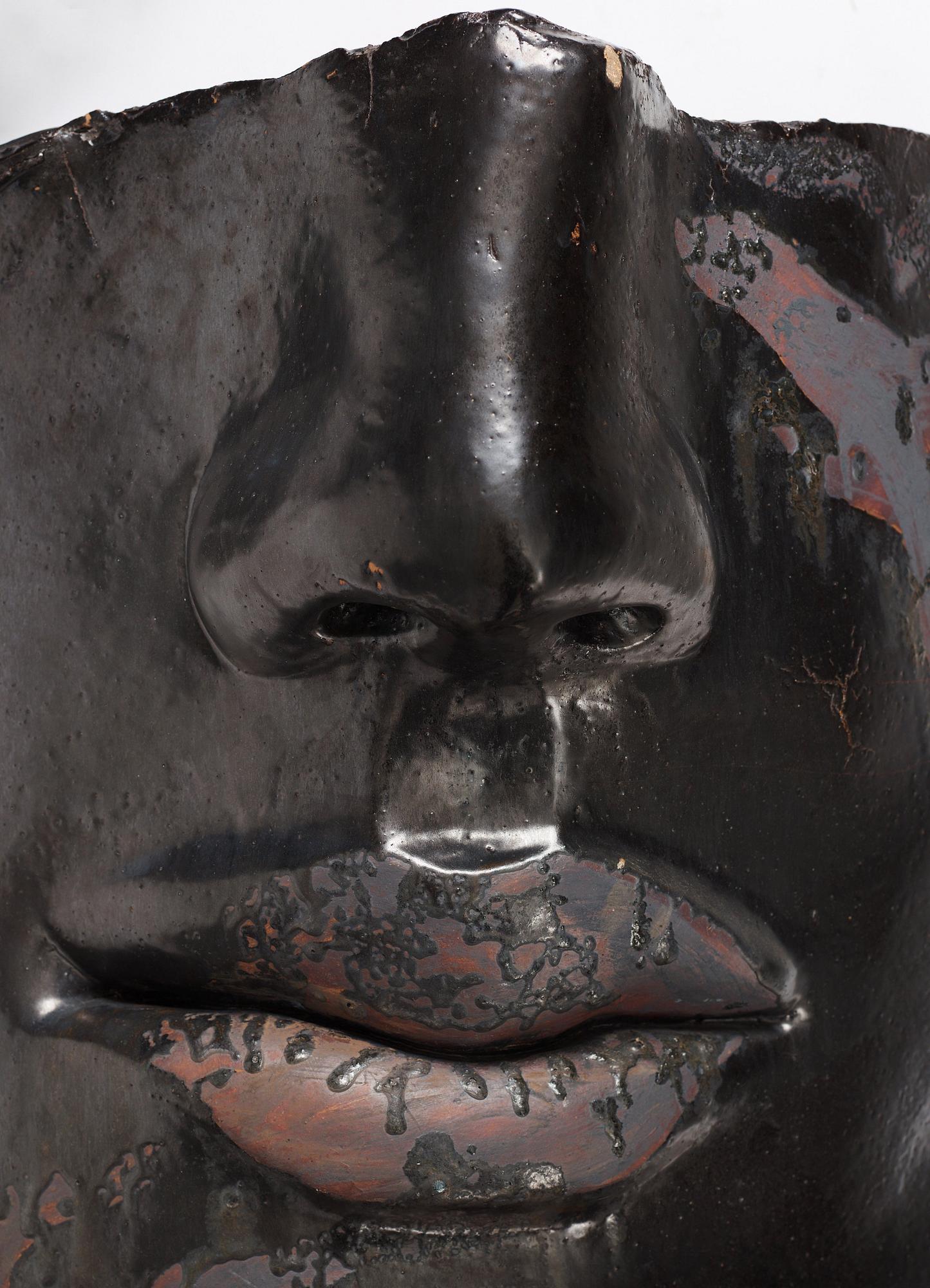 Hertha Hillfon, a black glazed stoneware wall sculpture in two parts of a face and a sky, executed in her own studio, Stockholm 1960s.