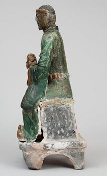 A green and yellow glazed pottery figure of a guardsman, seated on a postament, Ming dynasty.