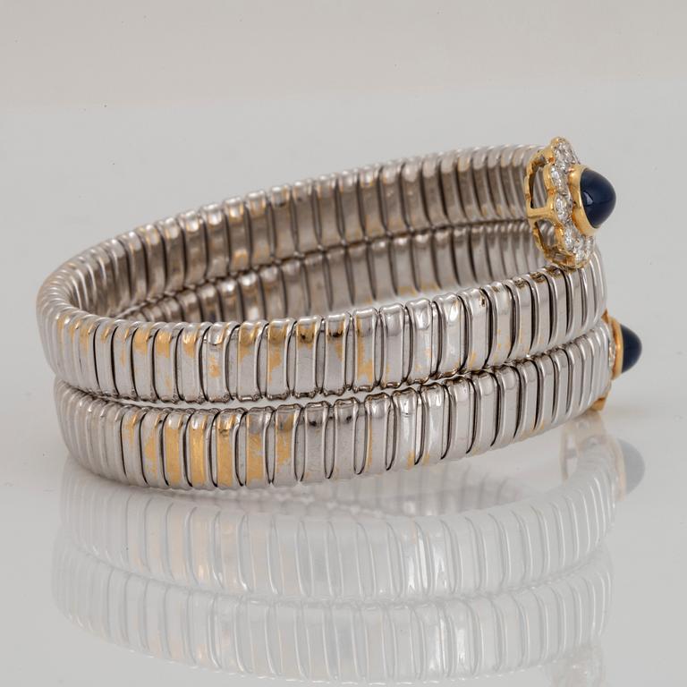 An 18K gold bangle set with cabochon-cut sapphires and round brilliant-cut diamonds.