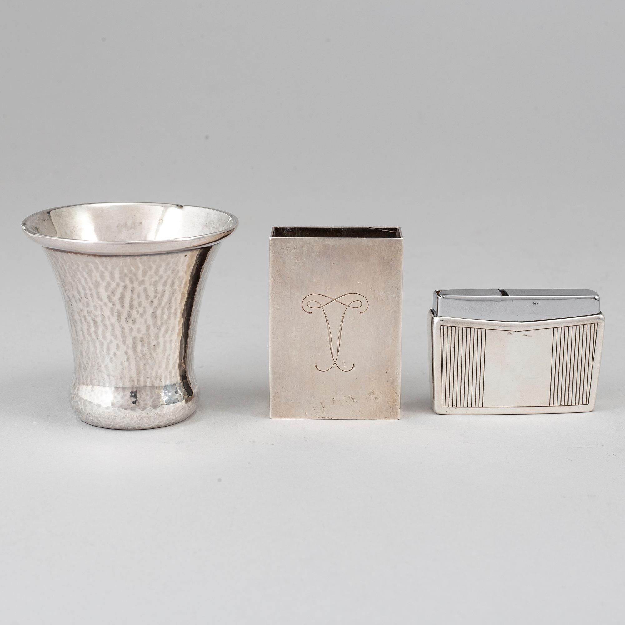 A silver vodkacup, lighter and matchholder.