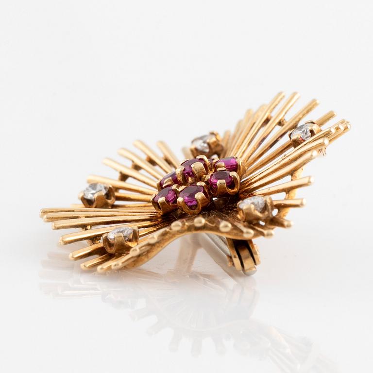 An 18K gold brooch set with round brilliant-cut diamonds and rubies.