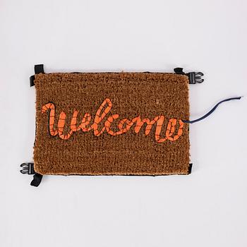 Banksy, Hand-stitched doormat using the fabric from life vests, 2019.