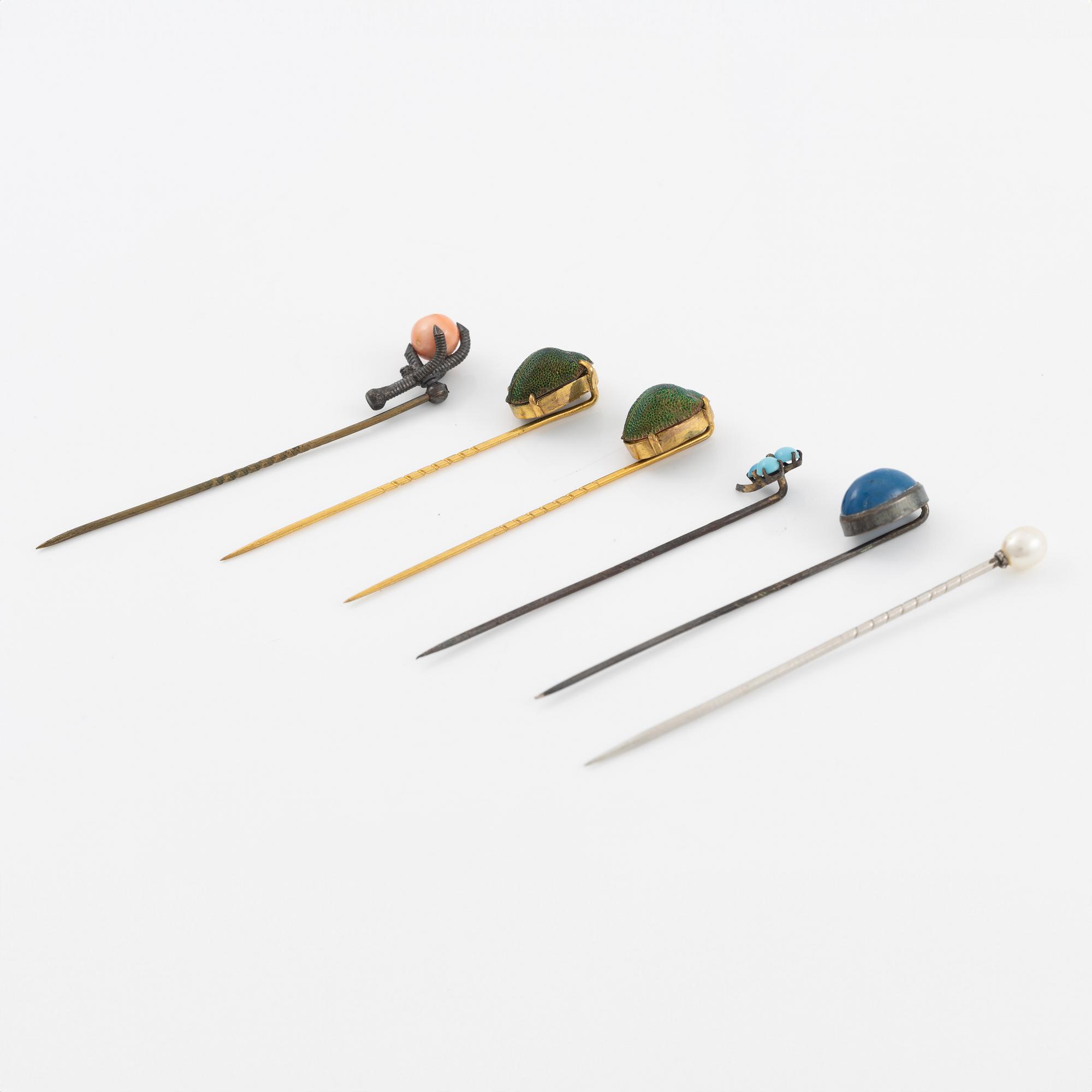 Six brooch pins in various designs and materials.