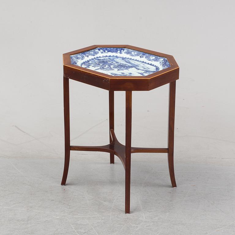 A mahogany veneered table with a Chinese blue and white porcelain charger, Qianlong (1736-95).