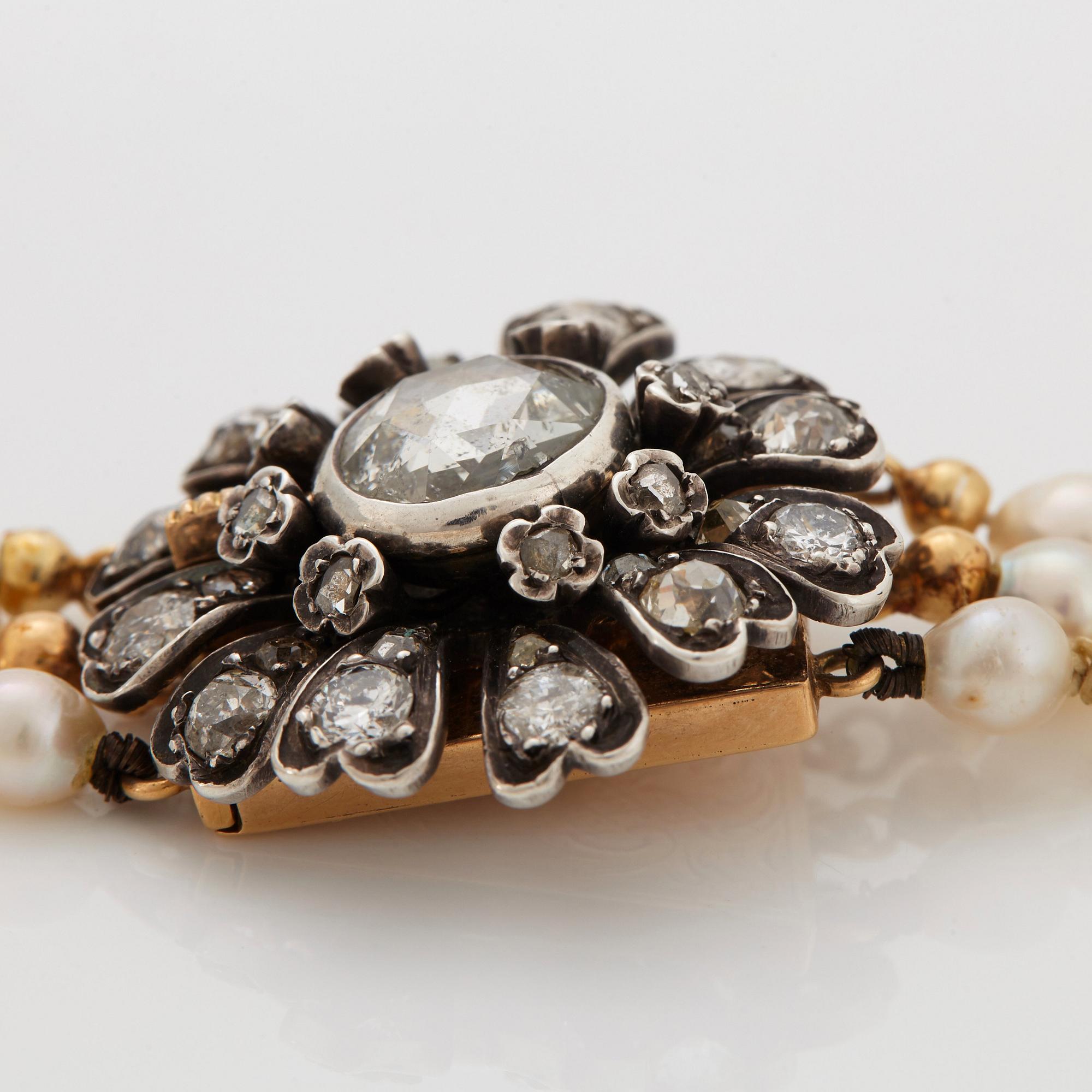 A three strand cultured pearl necklace with a clasp in 18K gold and silver set with rose- and old-cut diamonds.