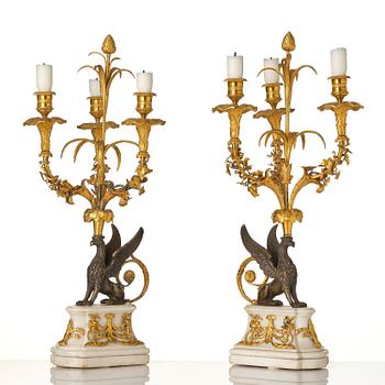 A pair of three-light Louis XVI patinated and ormolu candelabra in the manner of François Rémond, late 18th century.