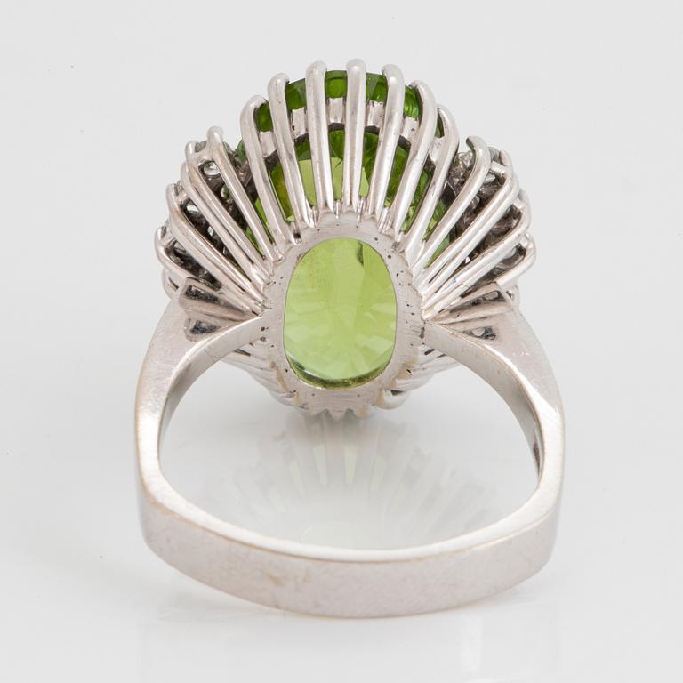 An 18K white gold ring set with an oval faceted peridot ca 11.00 cts and round brilliant-cut diamonds.