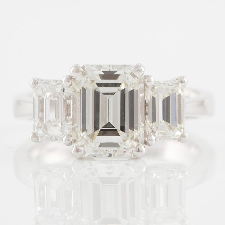 An 18K white gold ring set with three emerald-cut diamonds.