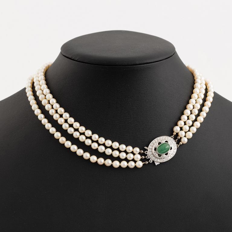 Three-row pearl necklace with cultured pearls, clasp with cabochon-cut emerald and brilliant-cut diamonds.