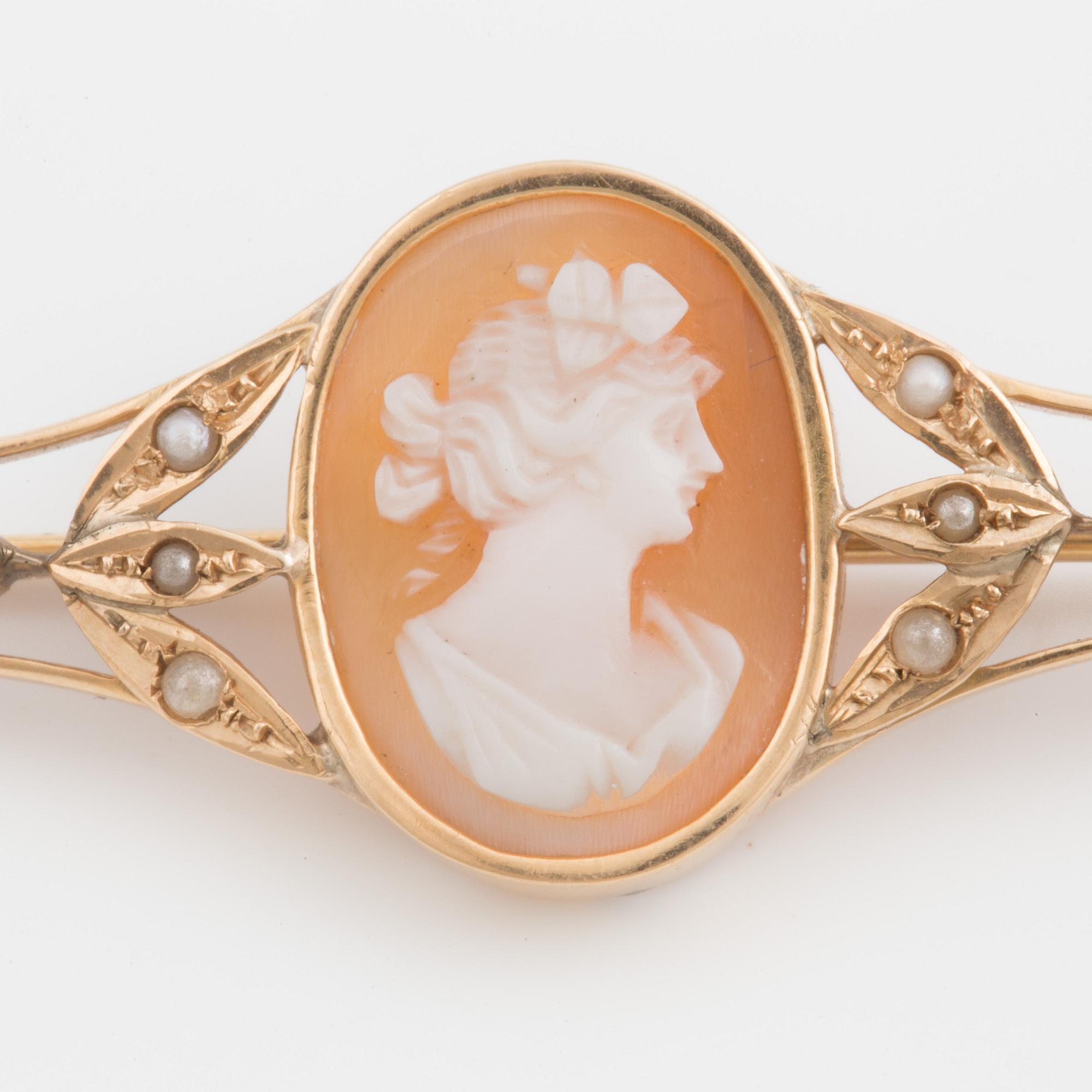 A brooch set with a shell cameo, seed pearls and probably synthetic rubies.
