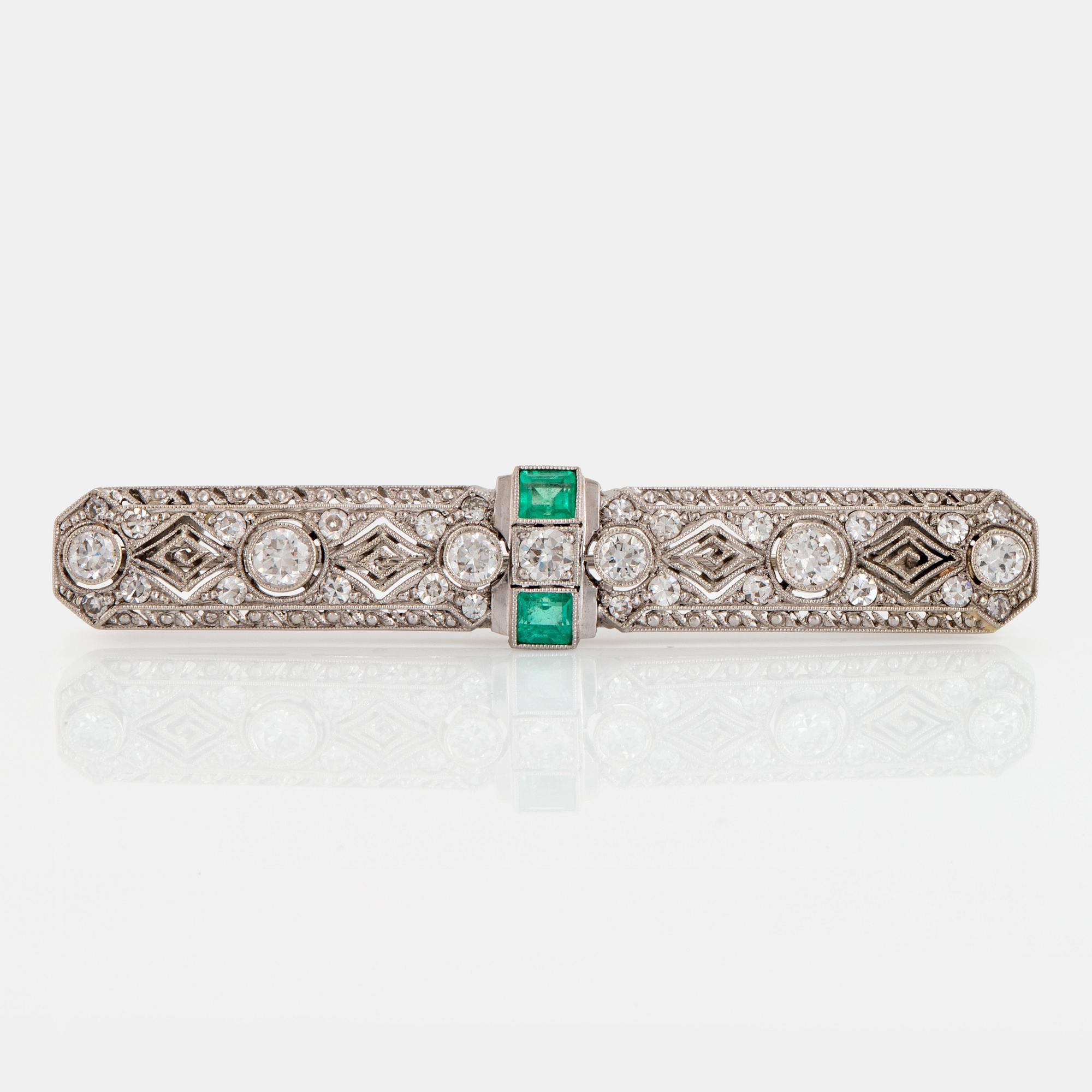 An 18K white gold brooch set with old- and eight-cut diamonds and faceted emeralds.