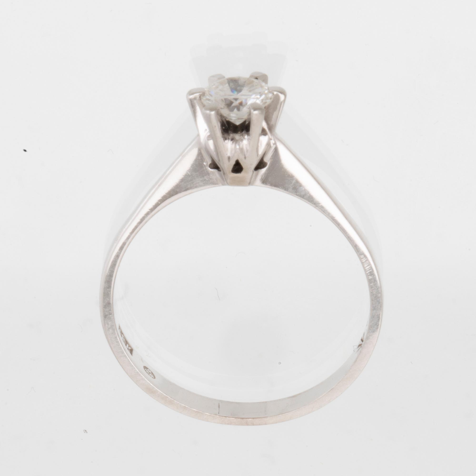 An 18K white gold solitaire ring set with a round brilliant-cut diamond.