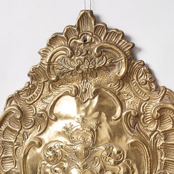 A pair of North European Rococo two-branch repoussé brass reflector plates, mid 18th century.