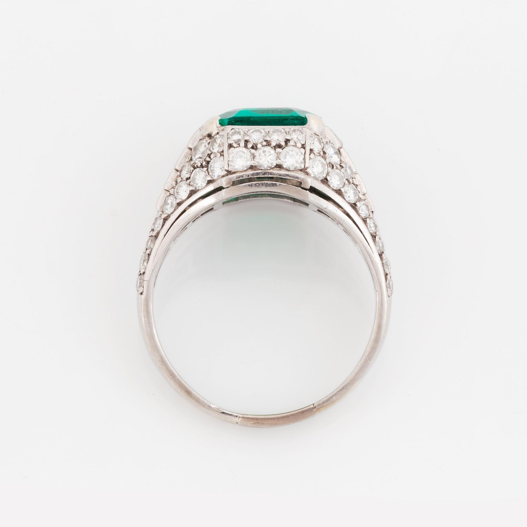 A Bulgari "Trombino" ring in platinum set with a step-cut emerald and round brilliant- and baguette-cut diamonds.