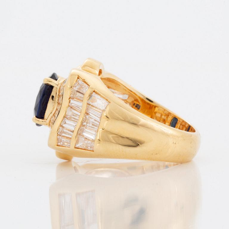 An 18K gold Junod ring set with a facted sapphire and tapered baguette-cut diamonds.