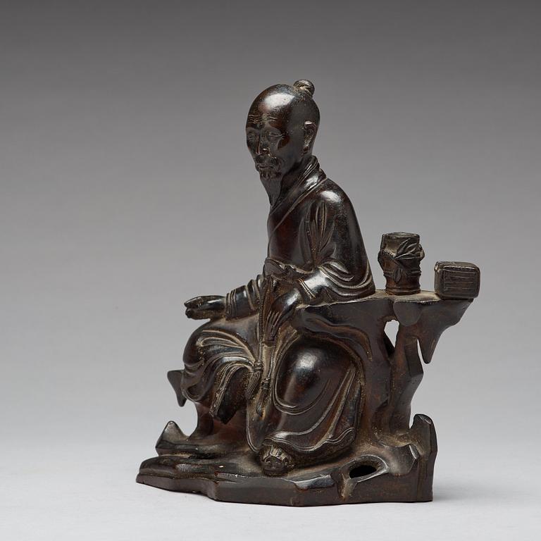 A bronze sculpture of a seated scholar with books, Qing dynasty (1644-1912).