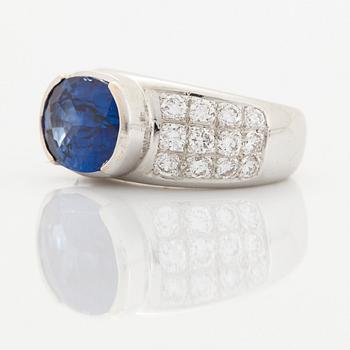 An 18K white gold ring set with an oval faceted sapphire and round brilliant-cut diamonds.