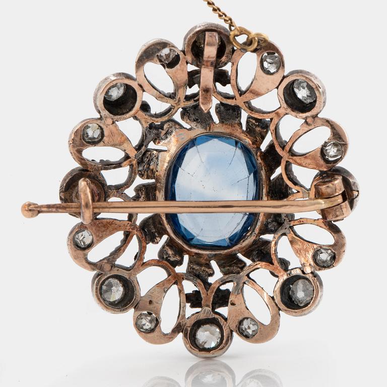 A 14K gold and silver brooch set with a synthetic sapphire and old- and rose-cut diamonds.