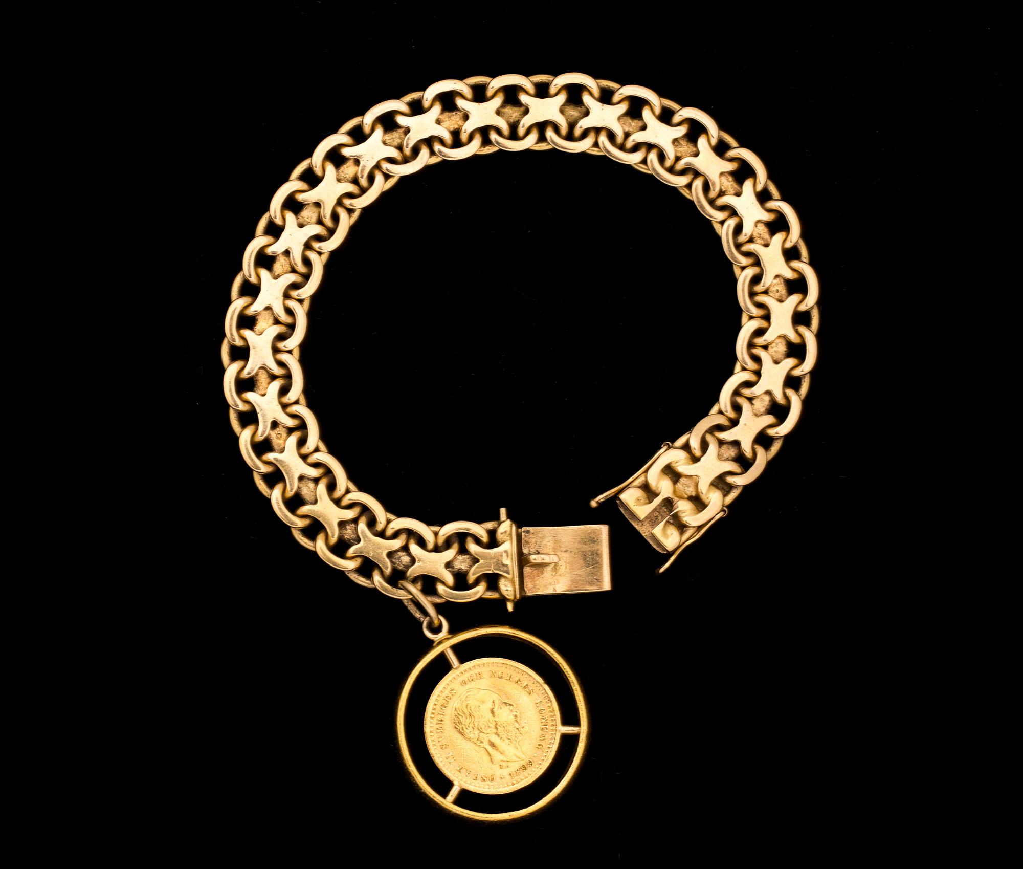 ARMLÄNK, 18 k guld med berlock i form av ett mynt. Vikt ca 34 g.