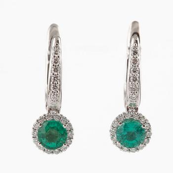 A pair of earrings with faceted emeralds and round brilliant-cut diamonds.