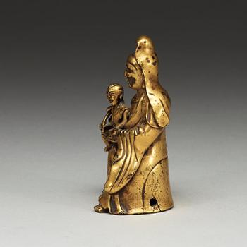 A seated gilt bronze figure of Guanyin with a small boy, Qing dynasty, 18th Century.