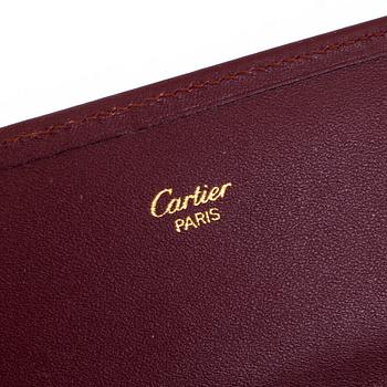 A clutch and a wallet by Cartier.