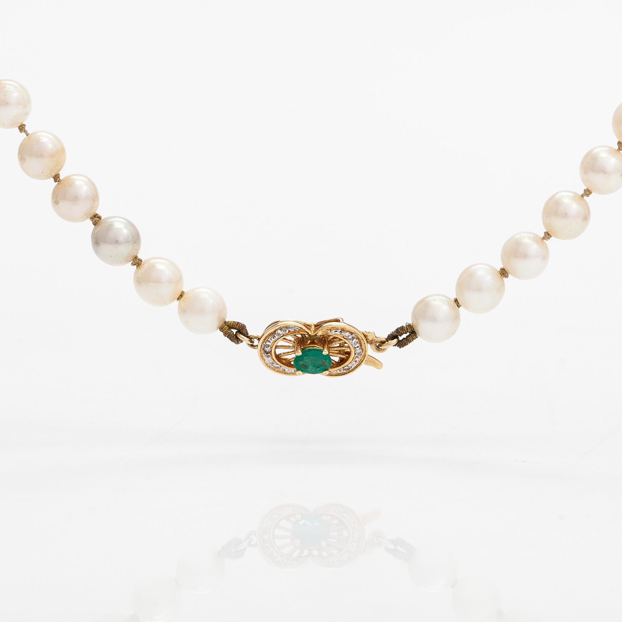 A cultured pearl necklace, clasp 18K gold with emerald and small diamonds.