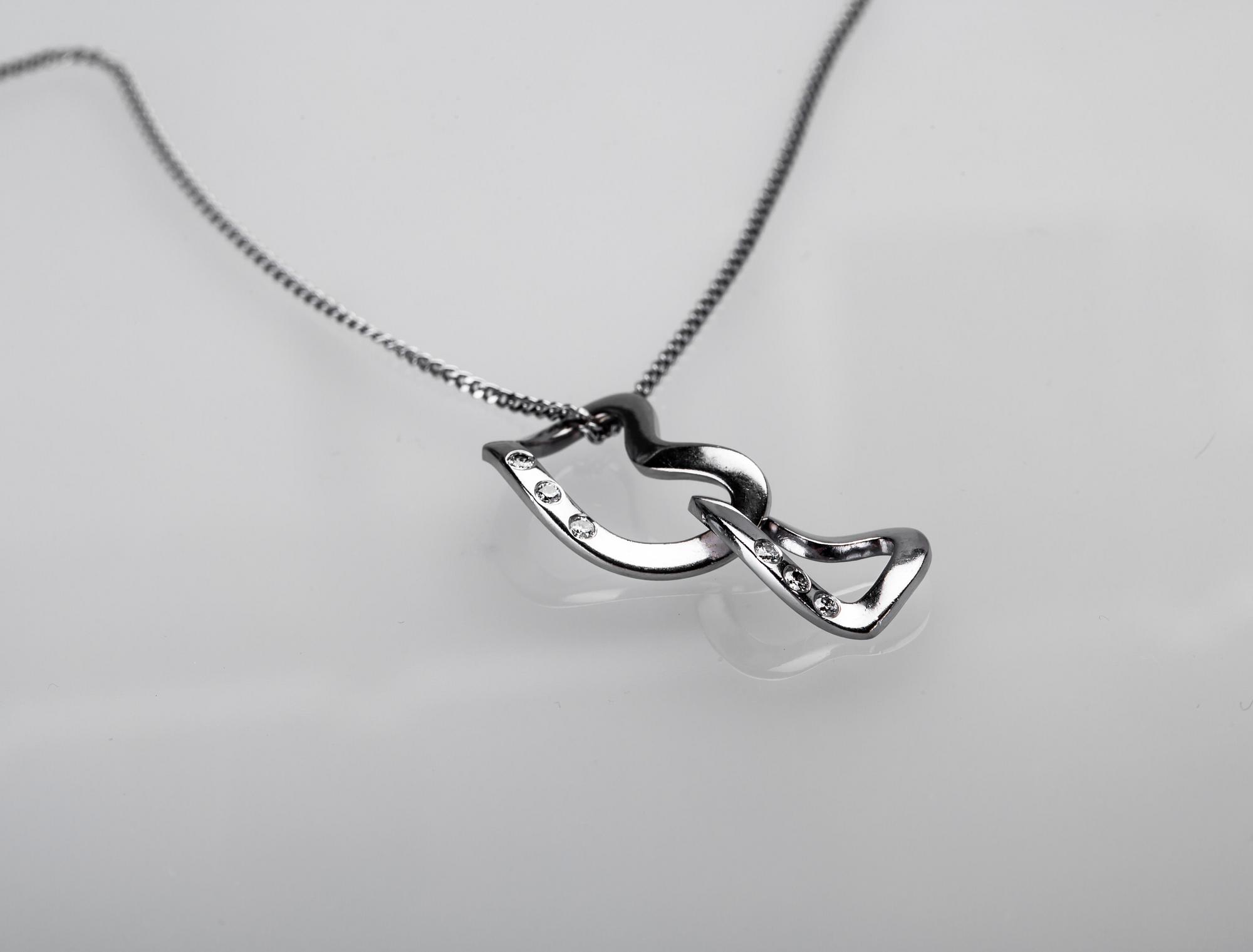 HÄNGE SAMT KEDJA, "Interlocking hearts", Regitze Overgaard för Georg Jensen, 18 k vitguld med diamanter. Vikt ca 7,5 g.