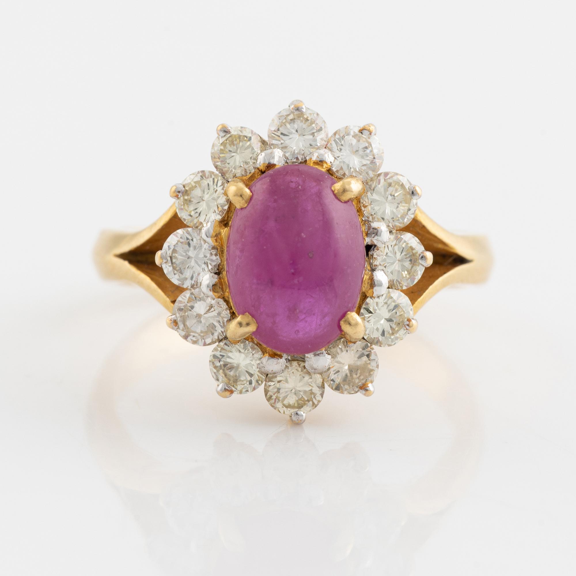 An 18K gold ring set with a cabochon-cut ruby and round brilliant-cut diamonds.