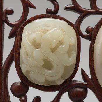 A set of four carved nephrite objects on a wooden frame, Qing dynasty (1664-1912).