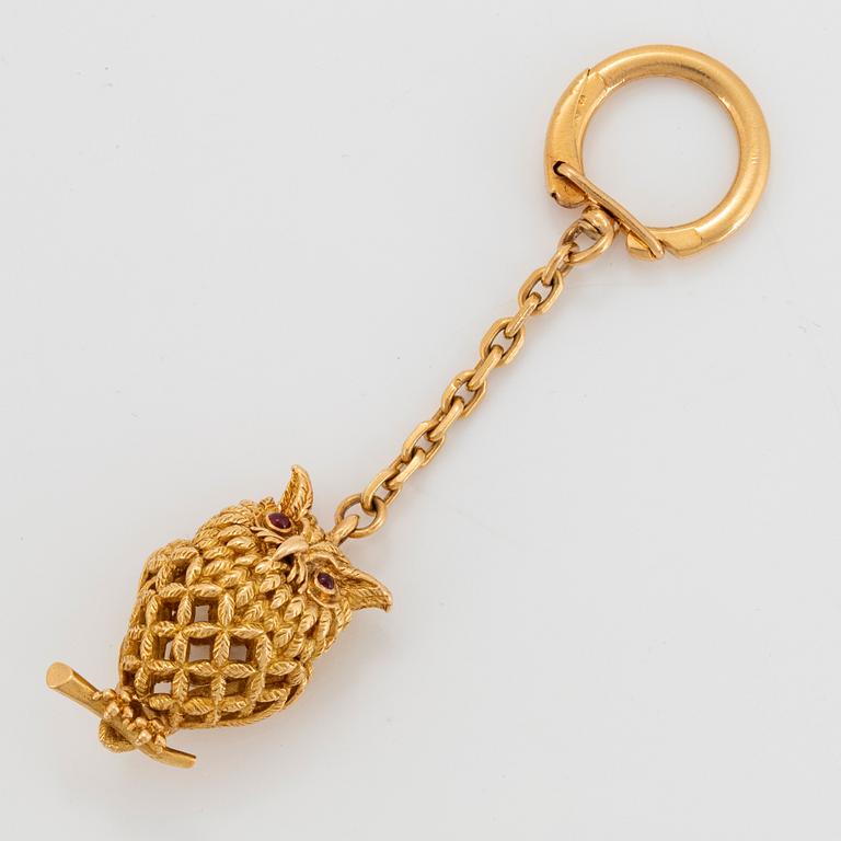 An 18K gold Hermès key chain in the form of an owl set with rubies.