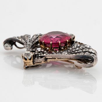 A silver and 14K gold brooch set with a faceted pink tourmaline and old- and rose-cut diamonds.
