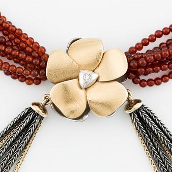 Ole Lynggaard, clasp in the shape of a flower, 18K gold with diamonds and two colliers, one in silver and gold with red stone beads.