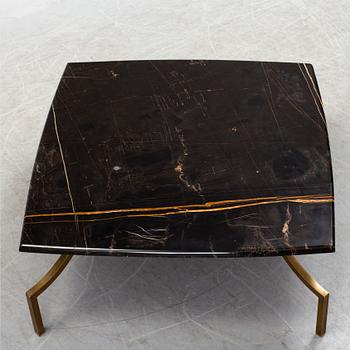 A modern Italian coffee table with black marble top on metal legs.