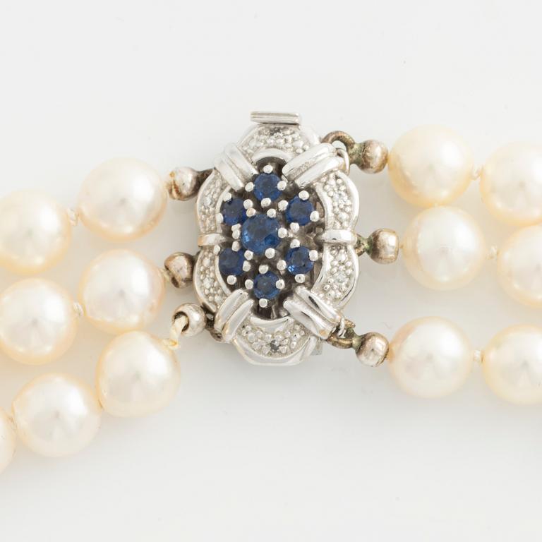 Collier, tre-radigt med odlade pärlor, lås i vitguld med safirer och små diamanter.