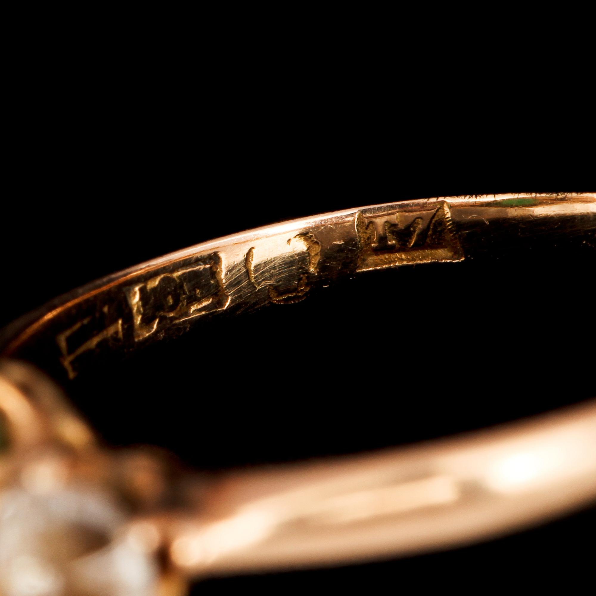 RING, 18K guld med fasettslipade vita stenar samt syntetisk smaragd, kattfotstämplad, 1921. Vikt 2,3 g.