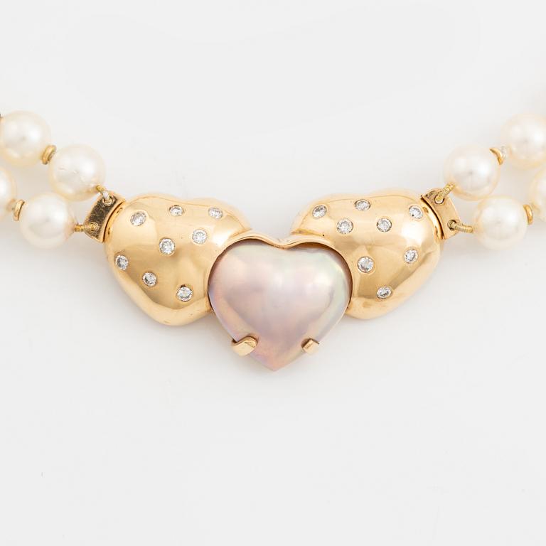 A two strand cultured pearl necklace with an 18K gold clasp with a half-pearl and round brilliant-cut diamonds.