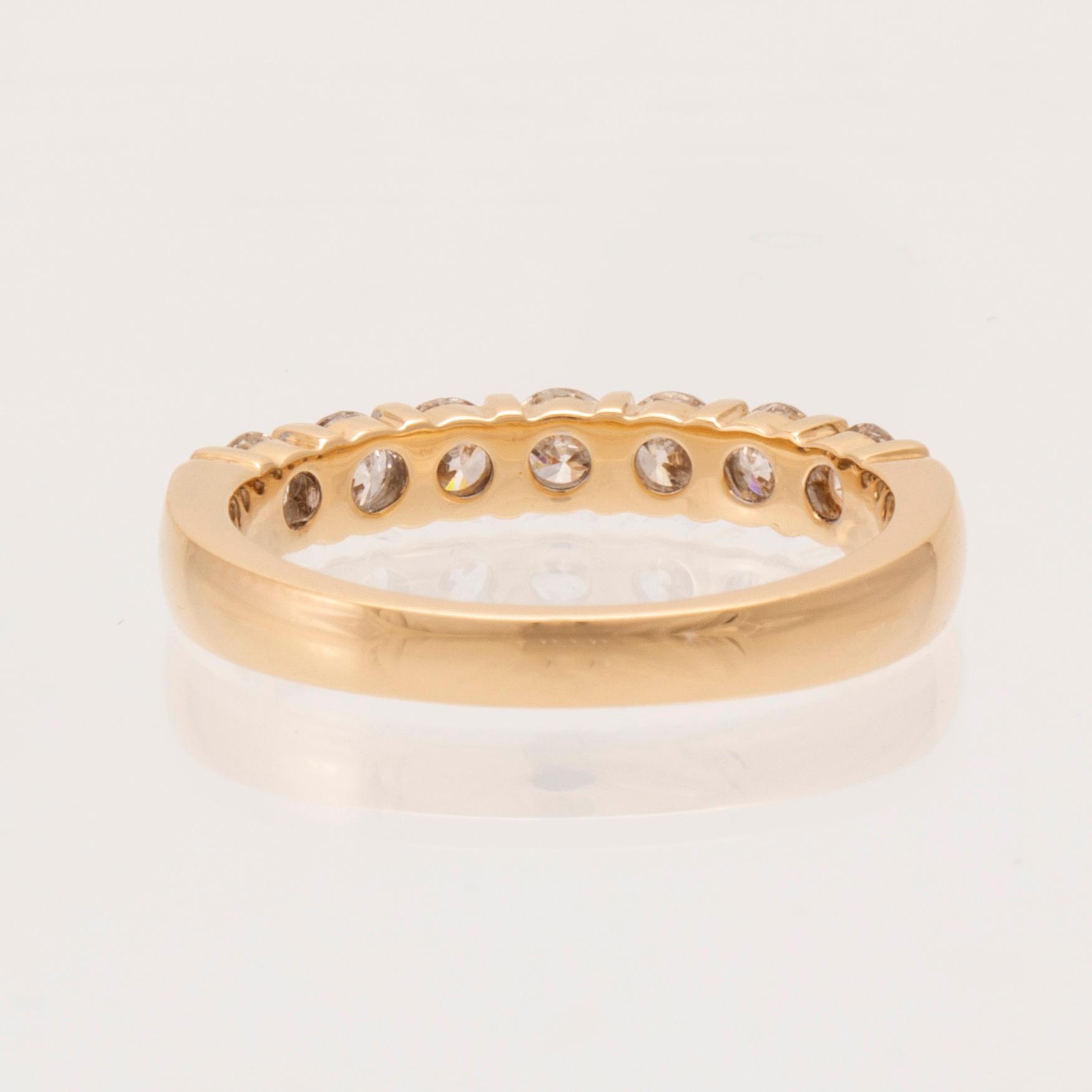 An 18K gold half-eternity ring set with round brilliant-cut diamonds.