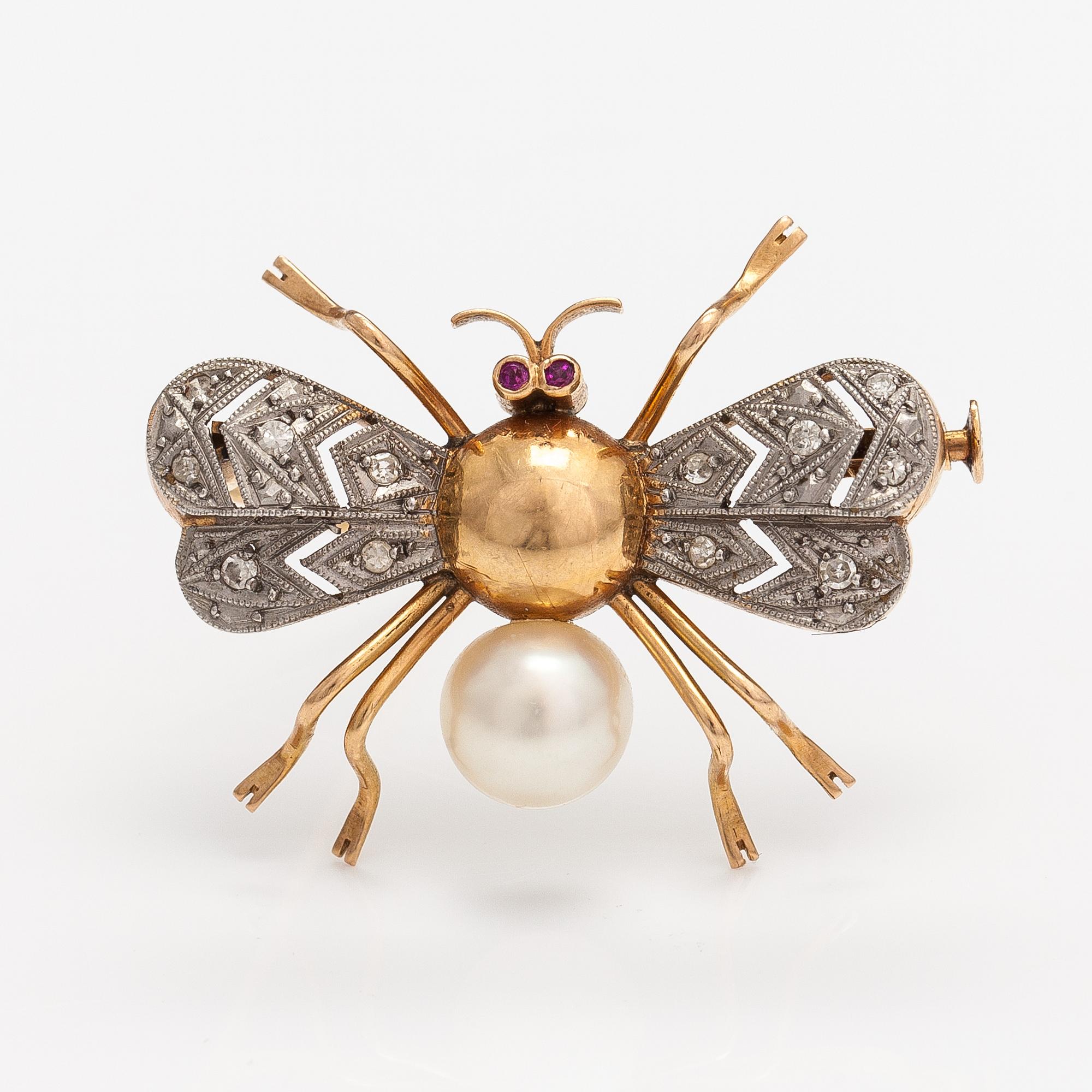 A 15-17K gold brooch with rubies, a cultured pearl and diamonds ca. 0.10 ct in total.