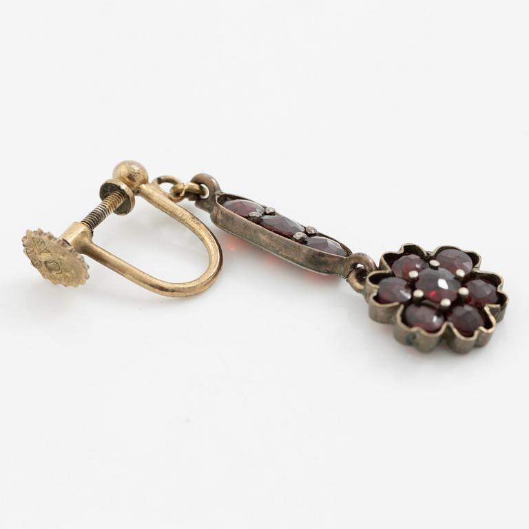 Garniture, necklace/bracelet and earrings in silver with garnets in the form of floral motifs, around the turn of the 20th century.