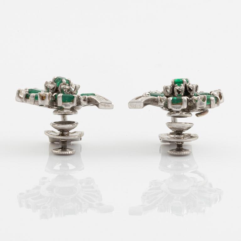 A pair of 14K white gold, emerald and round brilliant- and baguette cut diamond ear clips.