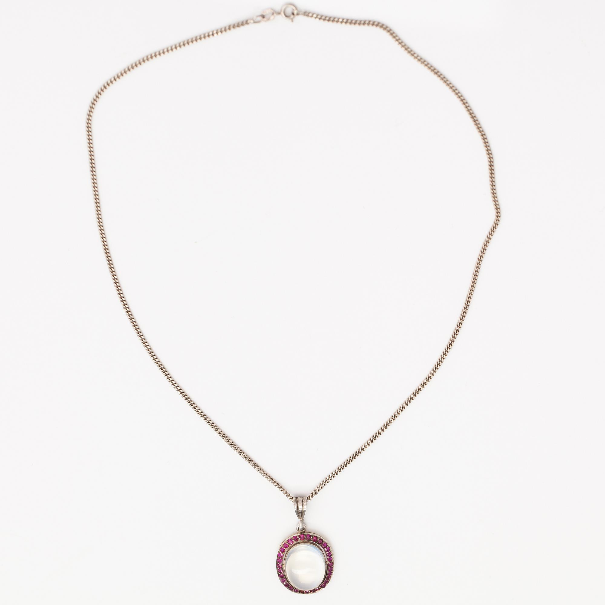 A 14K gold and silver necklace with a moon stone, rubies and a red glass stone.